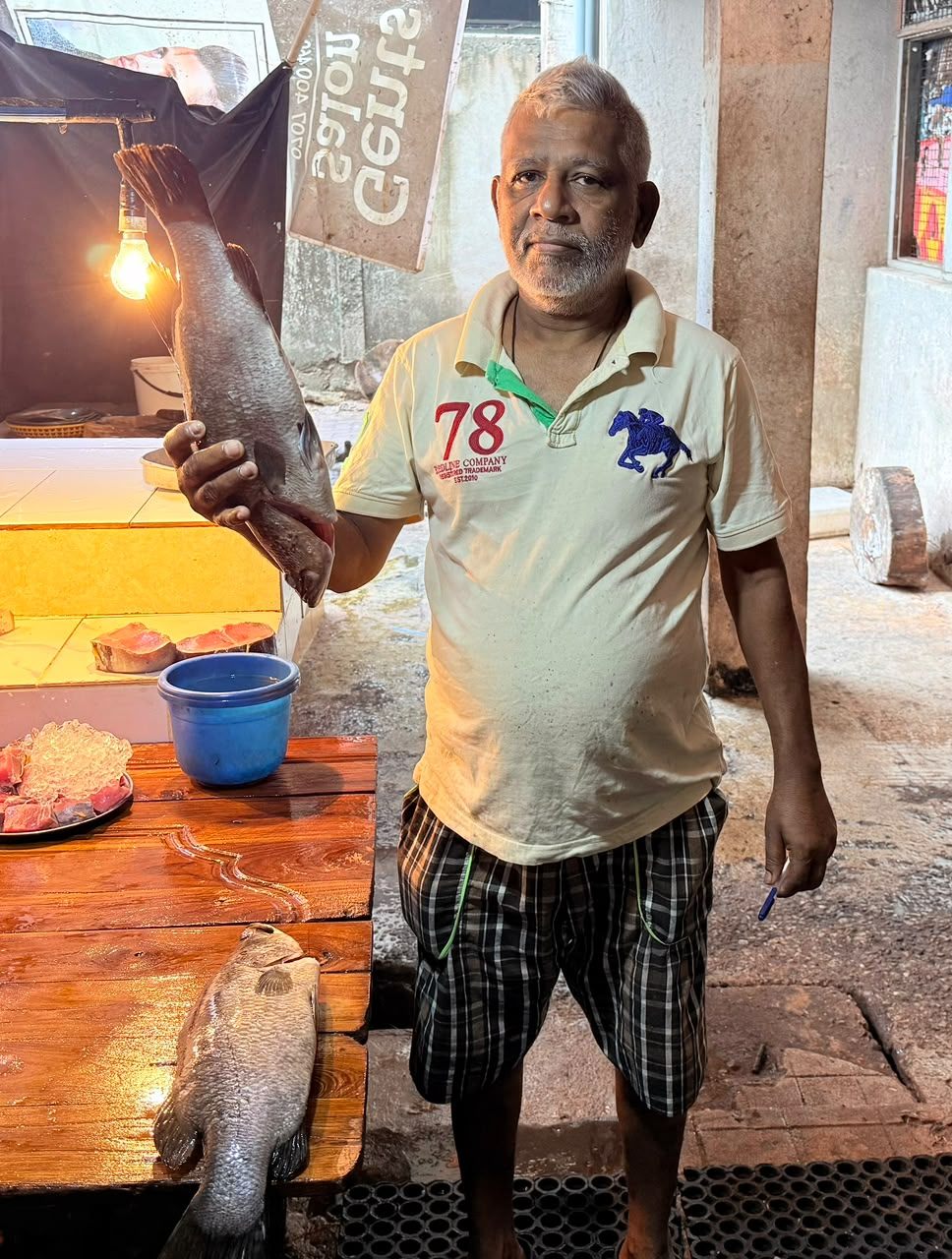 A vendor holding fresh fish at a Sri Lankan market